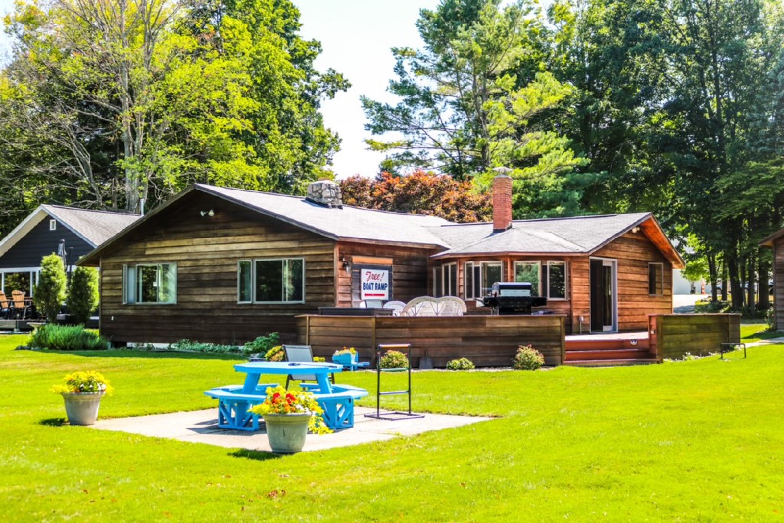The Boathouse cottage exterior with deck, grill and fire pit on Torch Lake